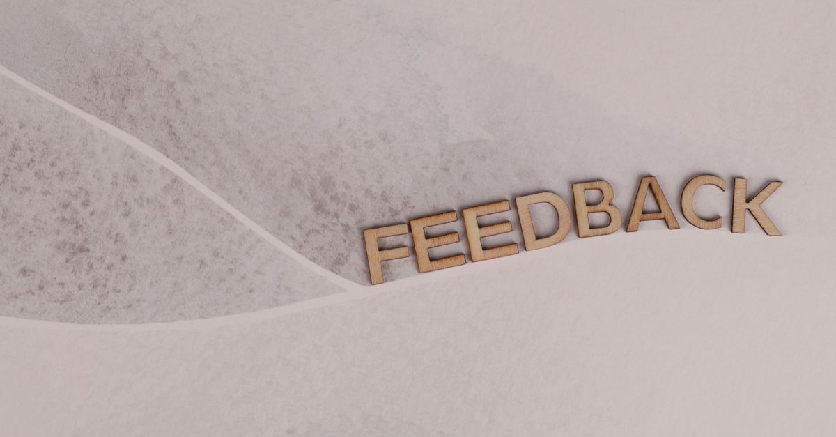 Wooden letters spelling 'FEEDBACK' arranged on textured paper background, conveying a conceptual theme.